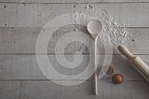 Rolling pin and wooden spoon for making dough, flour and egg on white wooden background. Isolated image. Image from above