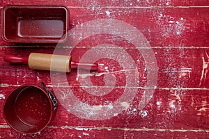 rolling pins, cookie cutters and flour on a red wooden background. View from above. Space for text
