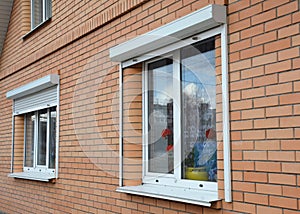 Rolling shutters house windows protection. Brick house with metal roller shutters on the windows