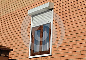 Rolling shutters house windows protection. Brick house with metal roller shutters on the windows