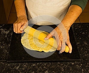 Rolling sourdough with a rolling pin on a black cutting board