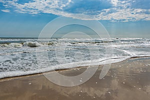 Rolling waves of the Atlantic Ocean under a sky with sun rays and clouds