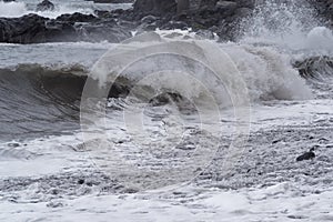 Rolling waves on stone coastline at stormy weather