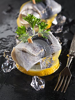 Rollmop herring on lemon slices and ice cubes
