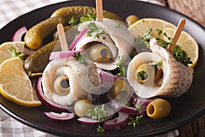 rollmops herring with olives, onions, pickles and lemon close-up. horizontal