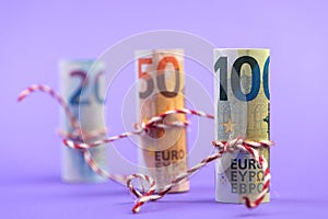 Rolls of 100, 50 and 20 euro money banknotes isolated on light purple