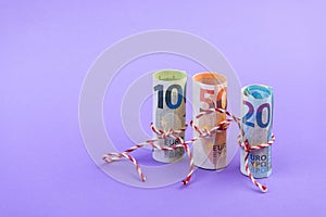 Rolls of 100, 50 and 20 euro money banknotes isolated on light purple