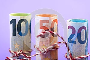 Rolls of 100, 50 and 20 euro money banknotes isolated on light purple
