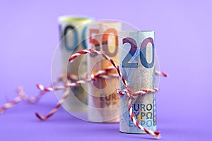 Rolls of 100, 50 and 20 euro money banknotes isolated on light purple