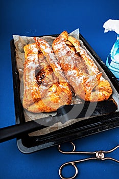 2 rolls of apple pie strudel on pan, tongs and sugar