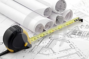 Rolls of architectural blueprints & tape measure
