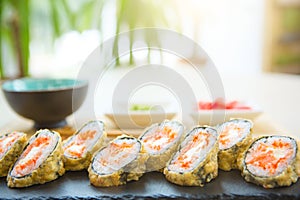 Rolls in a black plate on a wooden table. Fried sushi on black slate surface. Japanese food