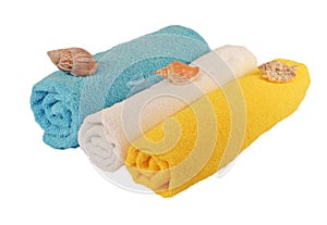Rolls of blue, white, yellow towels with sea shells isolated