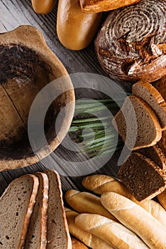 Rolls and breads on wooden table with wooden bowl, background for bakery or market