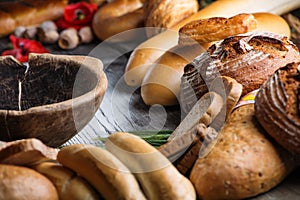 Rolls and breads on wooden table with wooden bowl, background for bakery or market