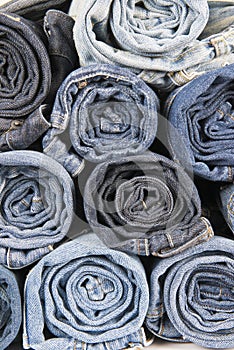 Rolls of different worn blue jeans stacked