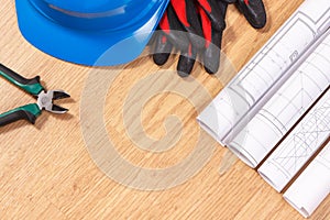 Rolls of electrical drawings, protective blue helmet with gloves and work tools, accessories for engineer jobs