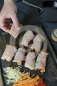 Rolls with fresh chicken breast with greens, carrot slices, bell peppers on a dark cutting board. The concept of healthy homemade