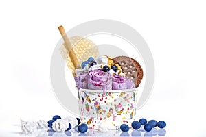 Rolls of ice cream with cookies and colorful decoration in a paper cup against a white background