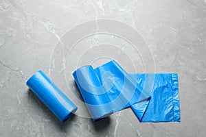Rolls of light blue garbage bags on grey marble table, flat lay. Space for text