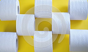 Rolls of new toilet paper lie on a yellow background