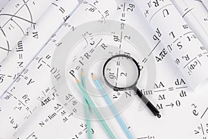 Rolls of paper drawings with math electrical formulas, magnifier and pencils