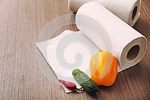 Rolls of paper towels with vegetables on kitchen table