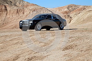 Rolls Royce car parked on unpaved road with mountains in background photo