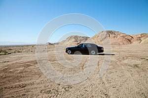 Rolls Royce car parked on unpaved road with tire tracks photo