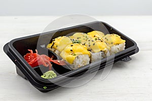 Rolls salmon, avocado, sesame seeds, cheese, green onions in a plastic container. Fast food, food delivery.