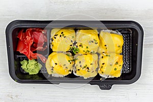 Rolls salmon, avocado, sesame seeds, cheese, green onions in a plastic container. Fast food, food delivery.