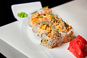 Rolls with salmon, mussels, cream cheese, cucumber, lettuce, green onions and sesame spice sauce on white plate