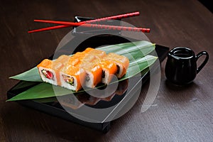 Rolls with salmon and tobiko on the board with sauce and red chopsticks