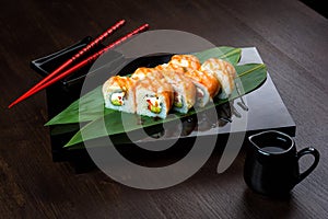 Rolls with shrimp and cucumber on the board with sauce and chopsticks