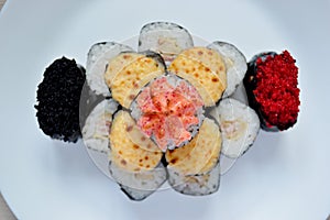 Rolls and sushi folded in the form of a cake on a white plate