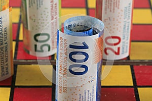 Rolls of Swiss banknotes placed on a chessboard