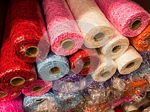Rolls of textured decorative wrapping paper of different colors on the shelf in the store