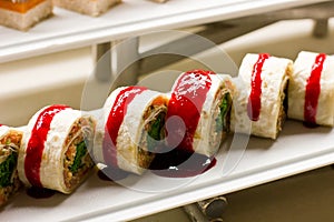 Rolls of thin tortillas stuffed with vegetables under tomato sauce