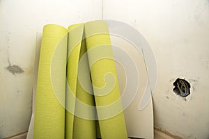 Rolls of wallpaper by plastered wall