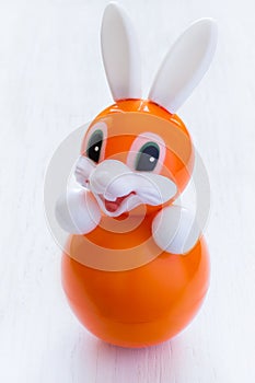 Roly-poly toy rabbit in orange on a white background