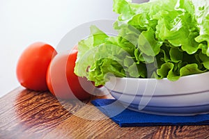 Romaine lettuce salad leaves and  tomatoes freshly washed on the dish close up ready for cooking