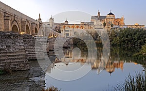 Roman bridge of the city of Cordoba in Spain with the background of the Mezquita in the early evening with well distributed lighti