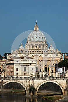 A Roman bridge over the Tiber river and in the background the Basilica of San Pietro in Rome - Italy