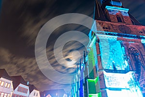 roman catholic basilica in germany at night in colorful illumination with moving clouds and neighboring houses