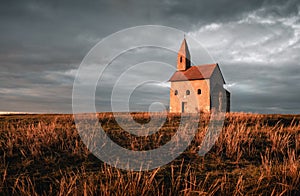 Old Roman Catholic Church of St. Michael the Archangelwith dark cloudy sky at Sunset - Drazovce, Slovakia