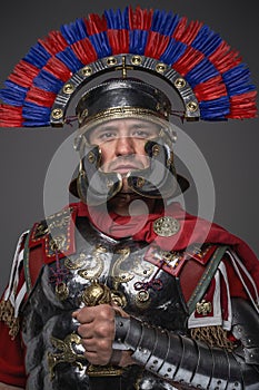 Roman legionary with sword posing against gray background