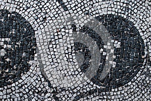 Roman mosaic with small black and white stones tiles representing a decoration. Detail of swirl depicted in a mosaic in Ostia Ant