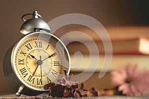 Roman Numeral in Vintage Alarm Clock and Stack of Book Background