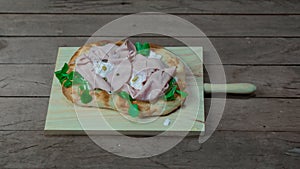 Roman pinsa, variant of the classic Italian pizza topped with mortadella, stracciatella and lamb\'s lettuce and pistachios