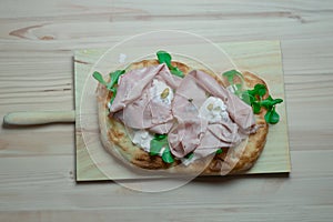 Roman pinsa, variant of the classic Italian pizza topped with mortadella, stracciatella and lamb\'s lettuce and pistachios